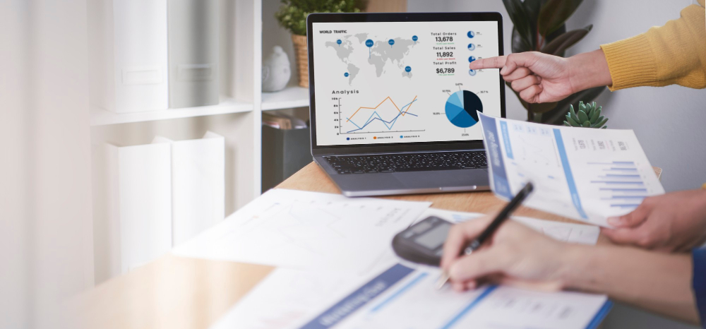 Business finance reporting papers and laptop showing charts and graphs representing Azure spend optimisation